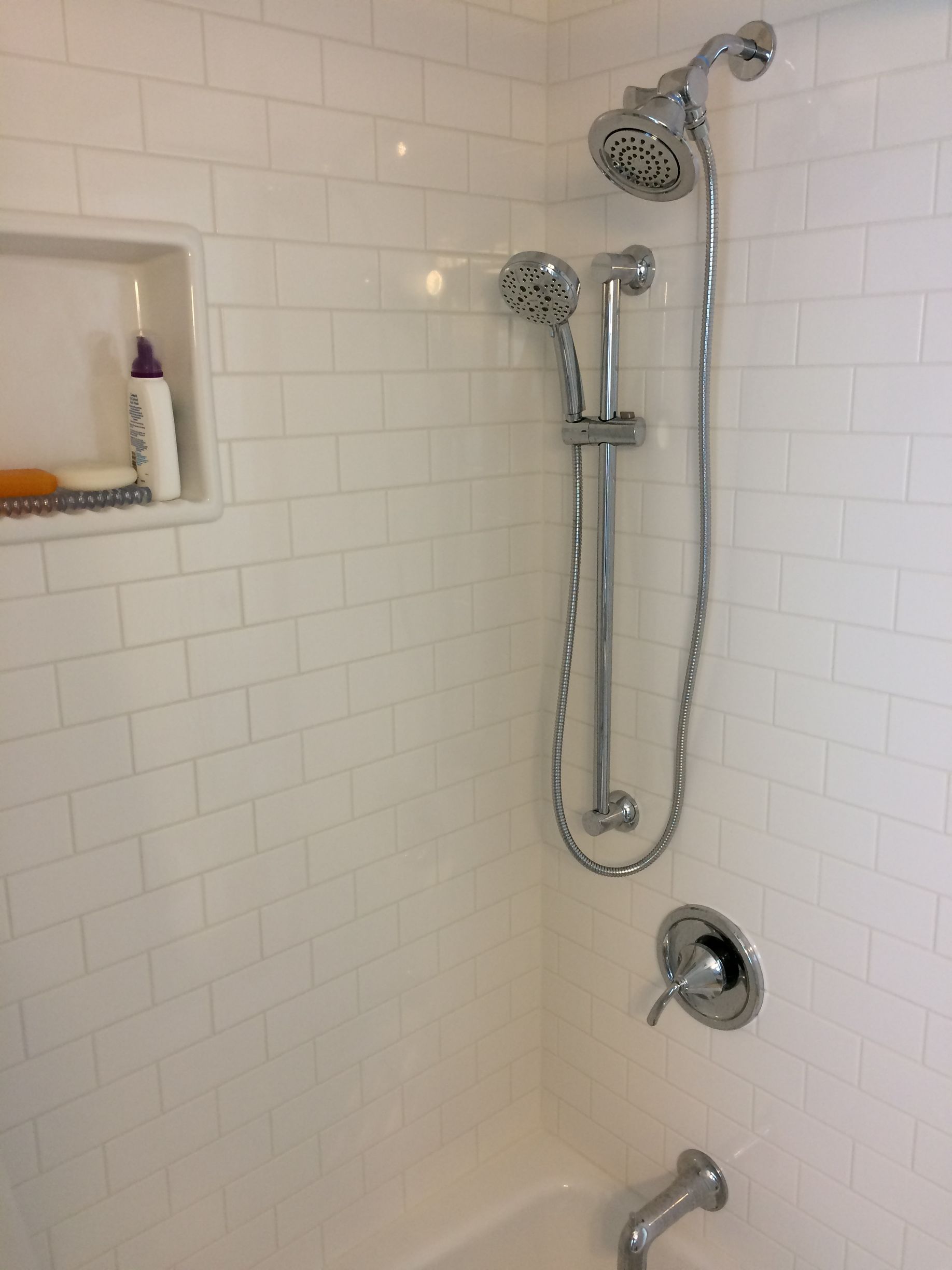 A shower with two shower heads and a bathtub.