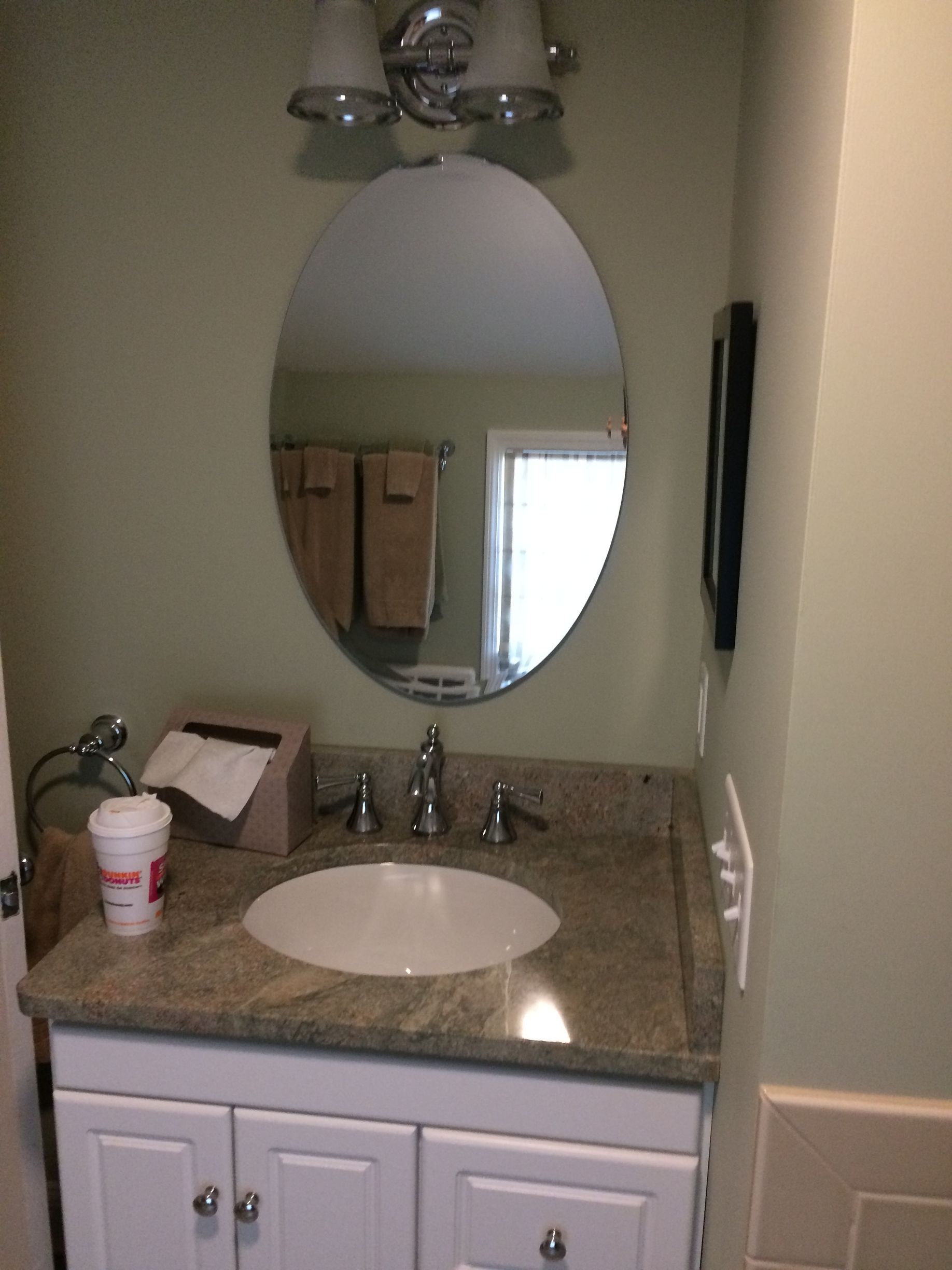 A bathroom with a sink and a round mirror