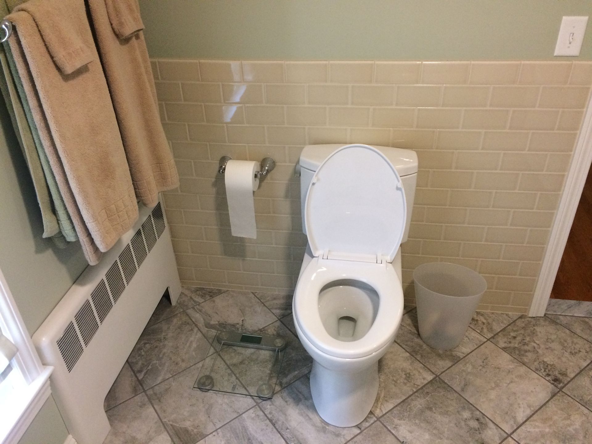 A toilet is sitting in a bathroom next to a trash can.