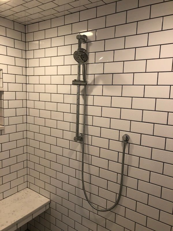 A bathroom with white tiles and a shower head