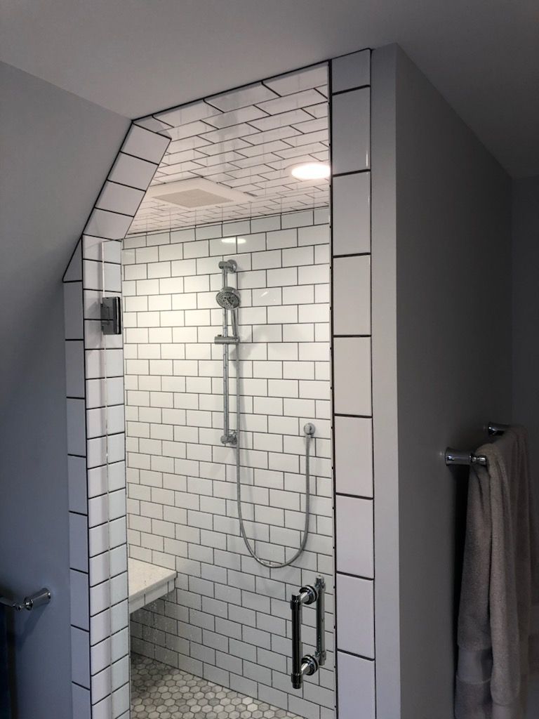 A bathroom with white tiles and a walk in shower