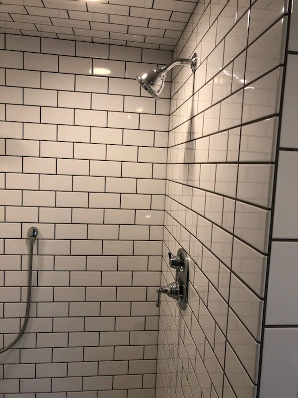 A shower with white tiles and a shower head