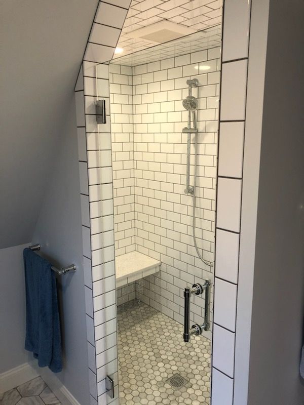 A bathroom with white tiles and a walk in shower
