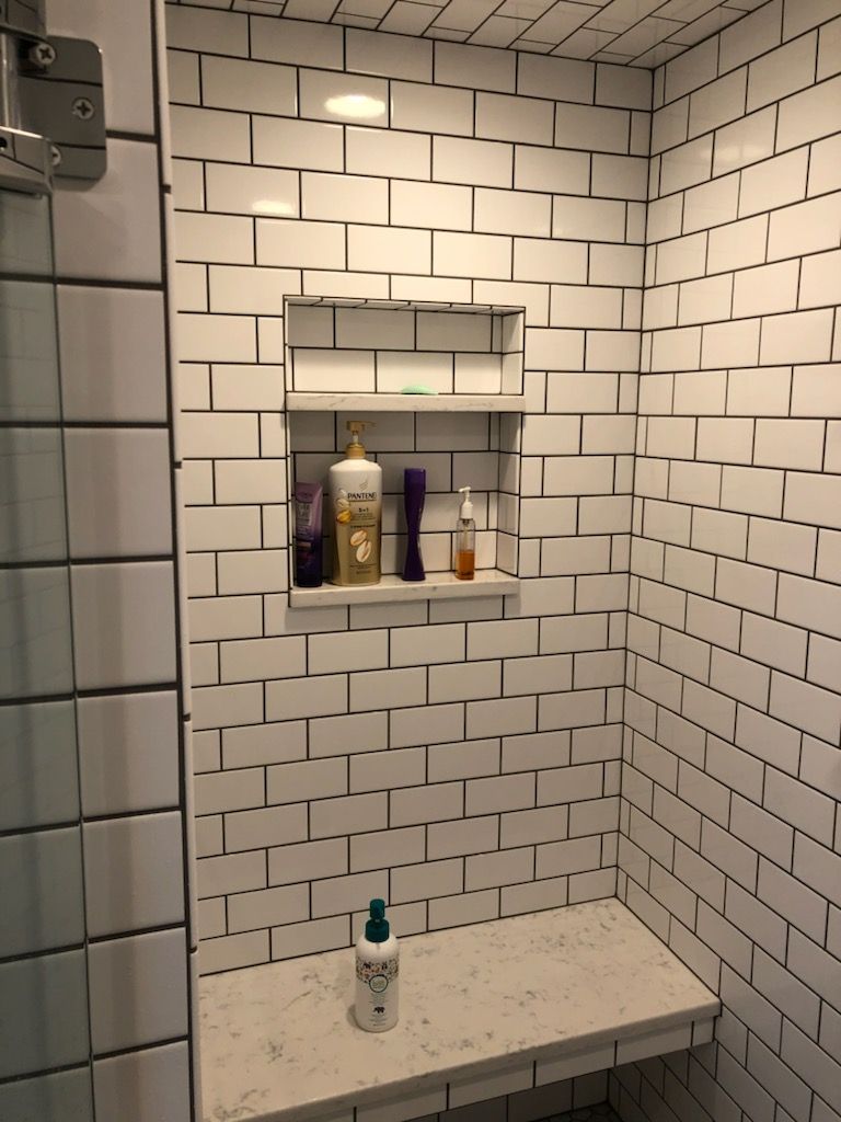 A bathroom with white brick walls and a bench