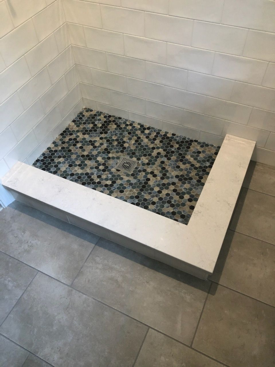 A walk in shower with a mosaic tile floor