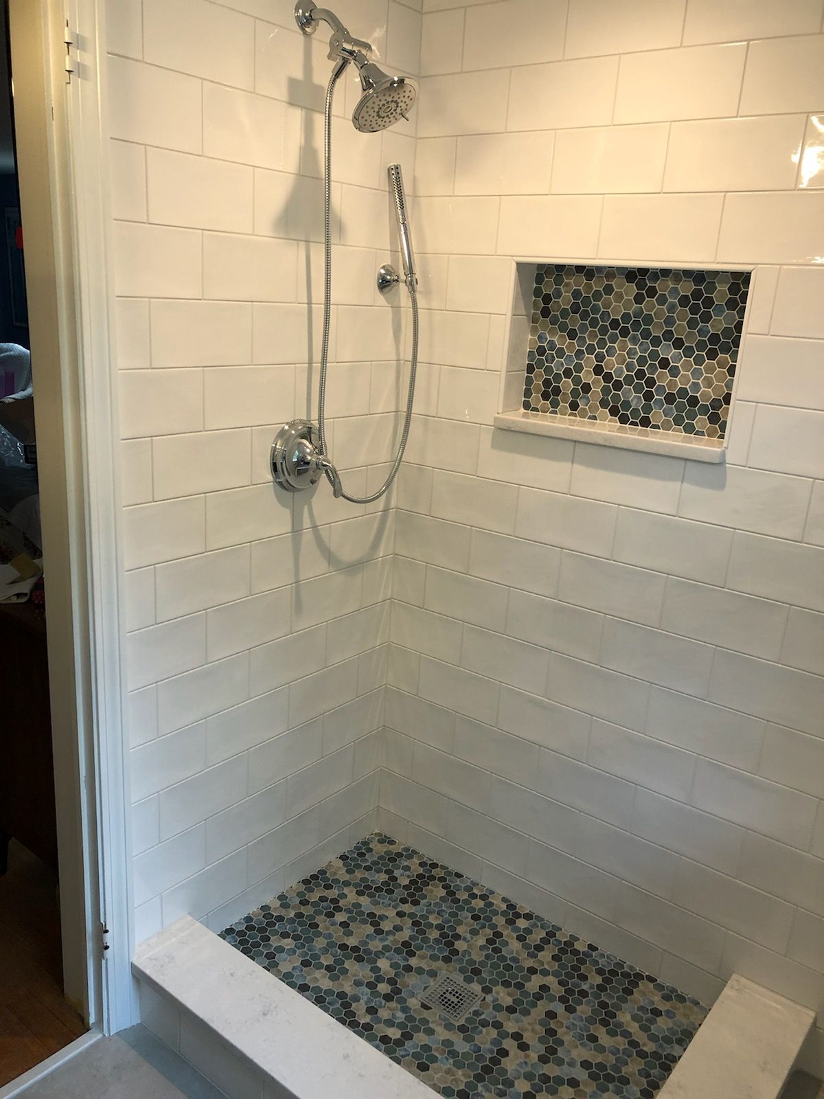 A shower with a shower head and a mosaic tile floor.