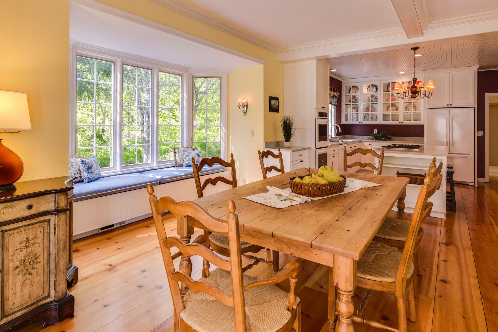 A dining room with a wooden table and chairs and a window seat.