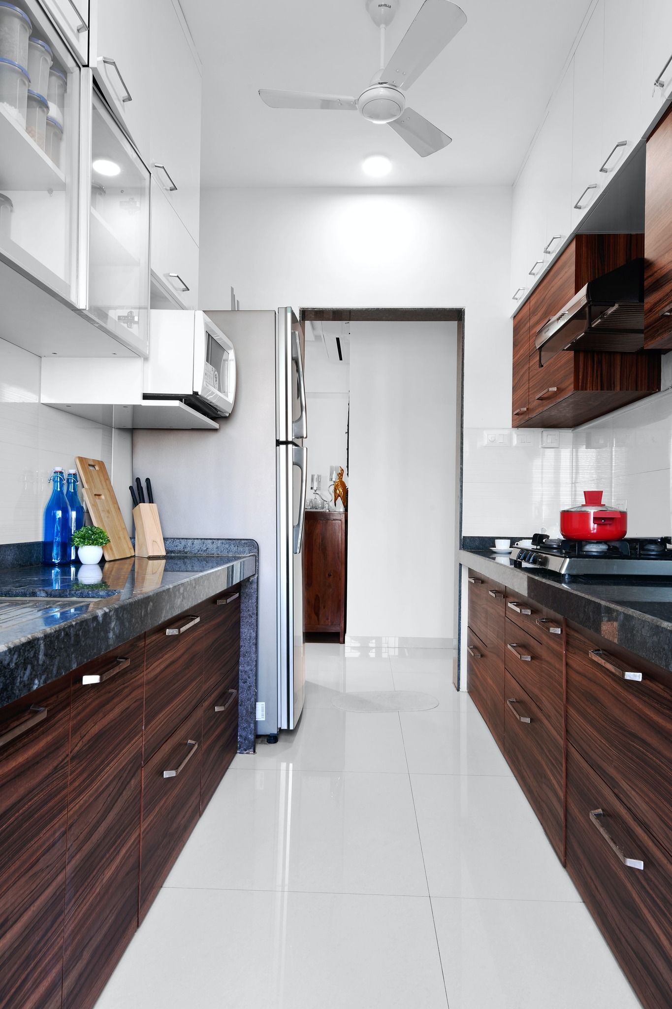 A long kitchen with wooden cabinets and a ceiling fan.