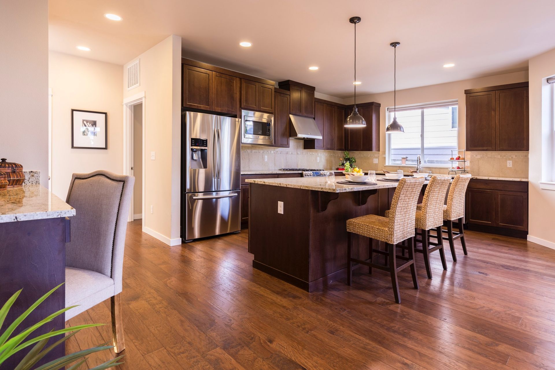 A kitchen with hardwood floors , stainless steel appliances , and a large island.