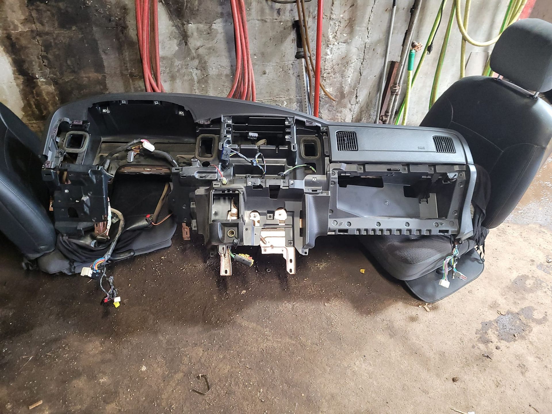 Dashboard and car seat removed from vehicle. Black, gray, and brown colors are visible. Wires are exposed.
