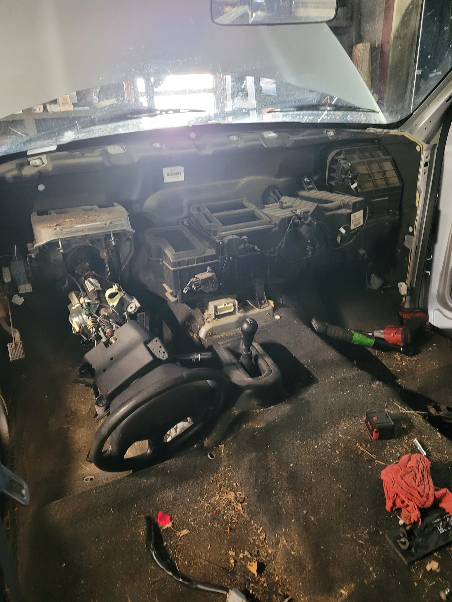 Car interior partially disassembled; dashboard, steering wheel, and central console visible.