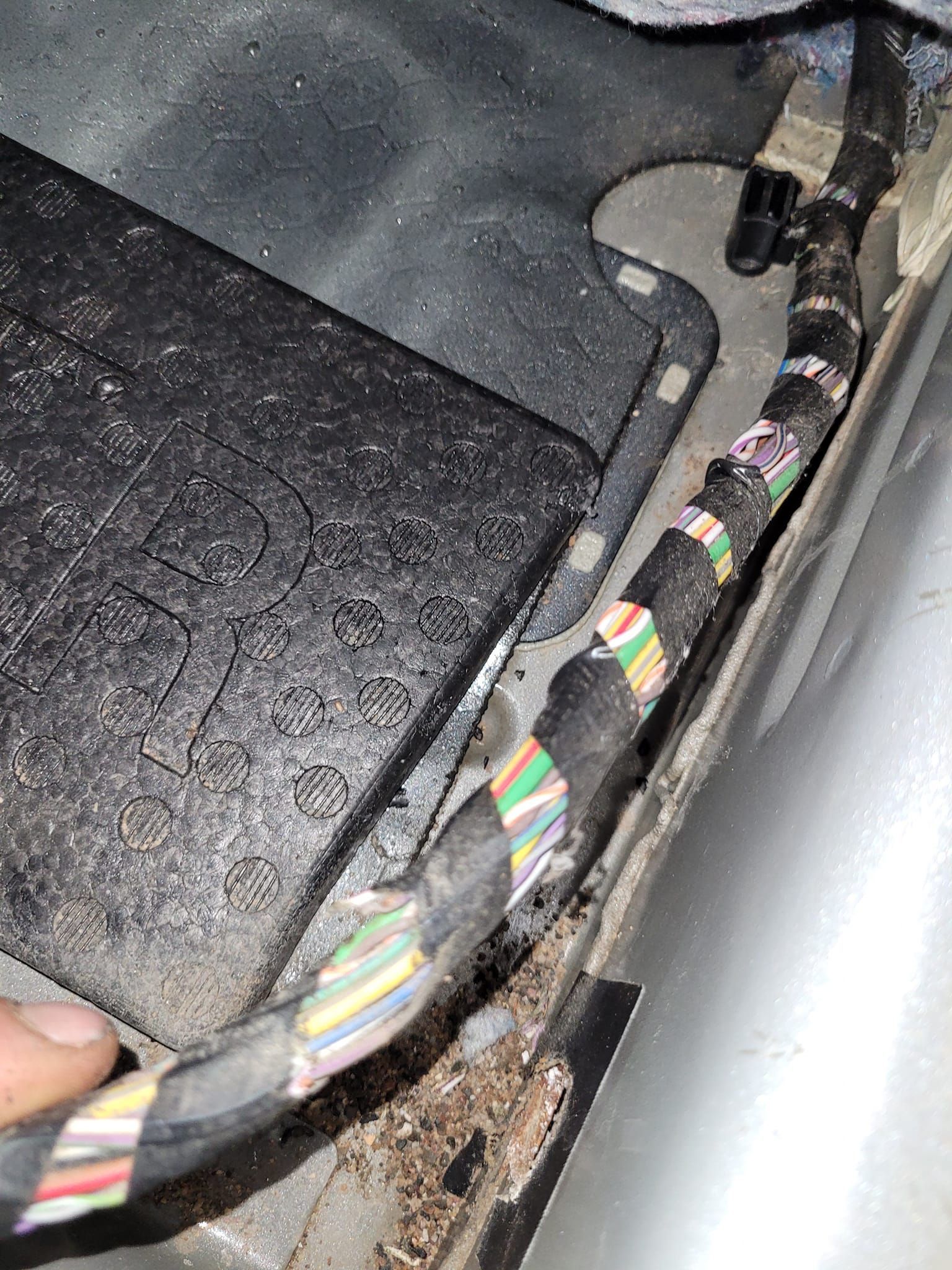Bundle of multicolored wires running along the side of a vehicle's interior.