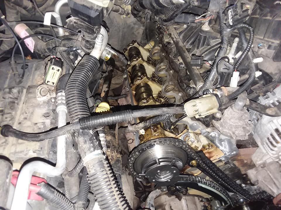 Car engine, partially disassembled. Visible are the camshafts, wiring, and various components.