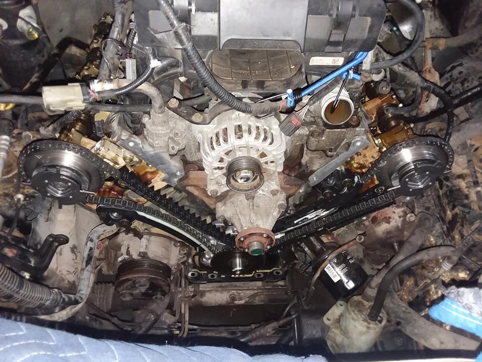 Engine with exposed timing chain components and oil stains.