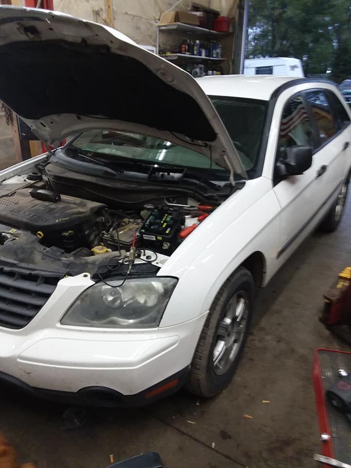 White Chrysler Pacifica with open hood in a garage.