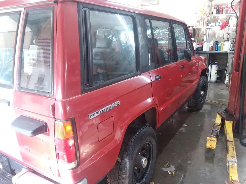 Red Isuzu Trooper SUV parked in a garage.