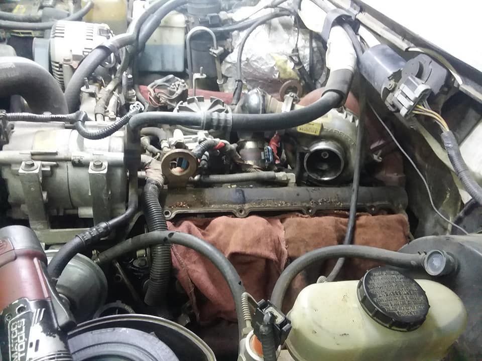 Open engine bay with visible hoses, engine parts, and tools.