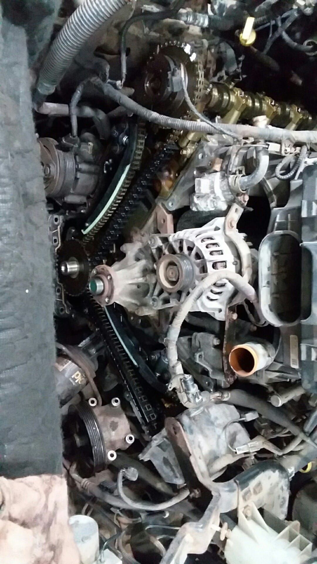 Engine compartment with timing chains, gears, and alternator visible. Dark, mechanical setting.