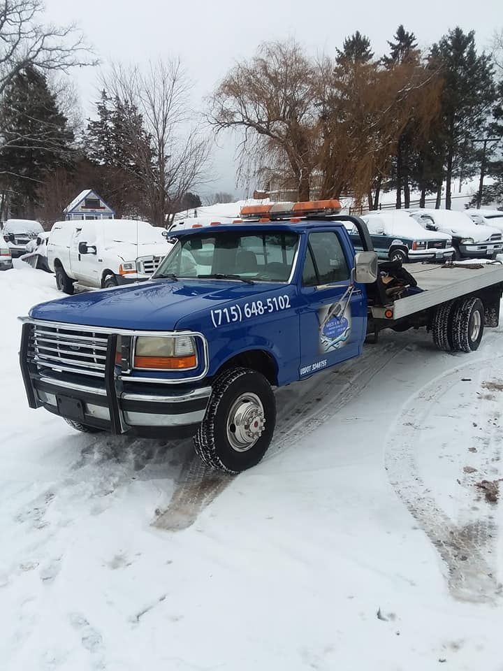 Blue tow truck on snowy ground, phone number visible.