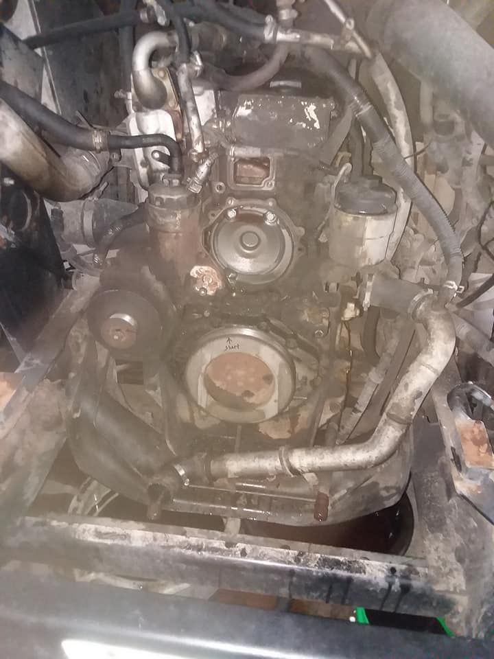 Dirty engine bay, front view, with various components and hoses visible.