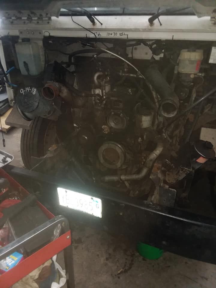 Engine of a vehicle with components visible and exposed, likely in a repair shop setting.