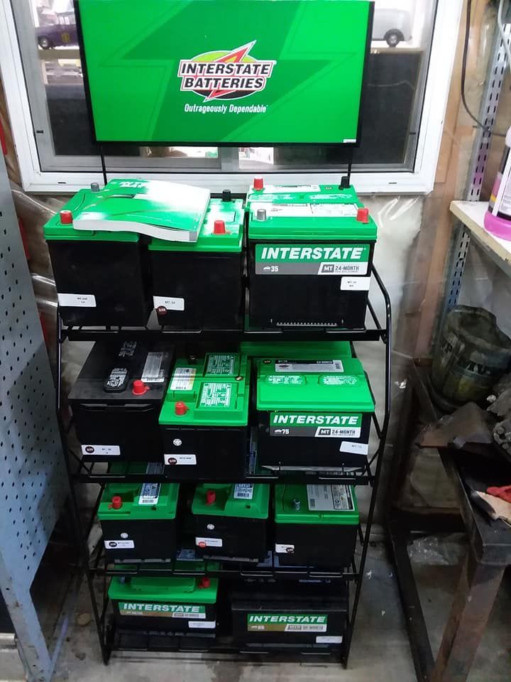 A display rack with various green and black Interstate car batteries. A green Interstate sign sits atop.
