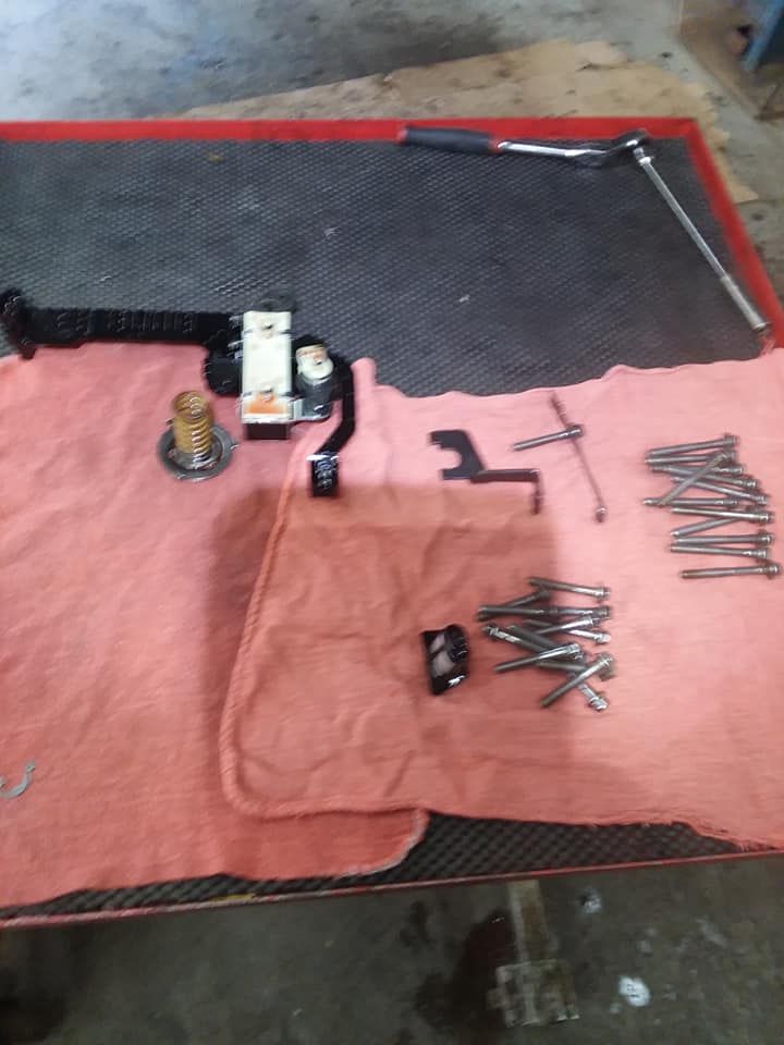 Tools and car parts laid out on a table with a red towel, likely for repair.