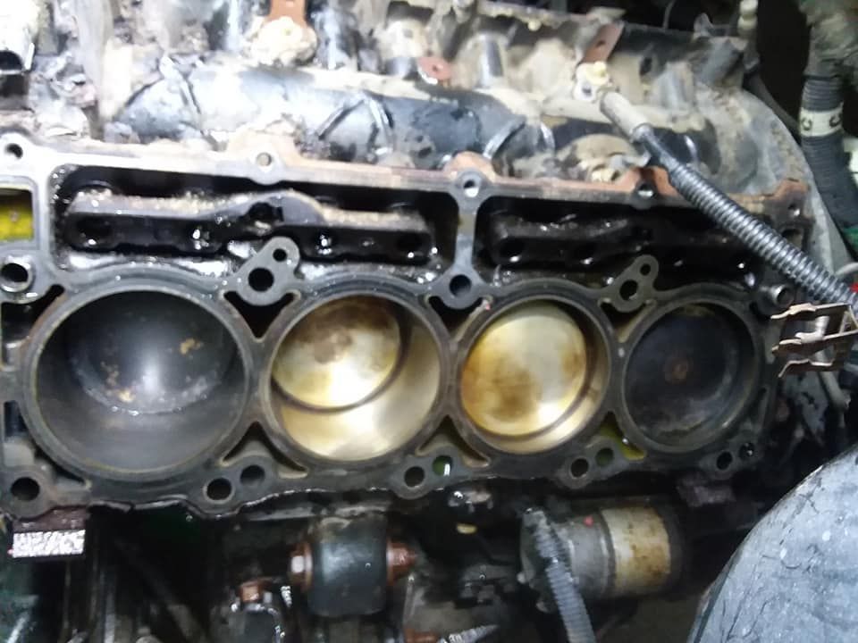 Engine block with exposed cylinders, showing wear and oil residue.