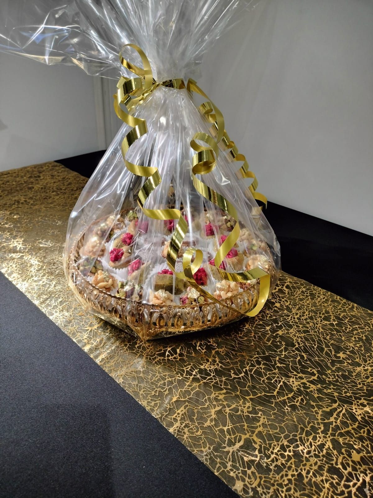 Un panier rempli de mignardises est emballé dans du plastique et posé sur une table.