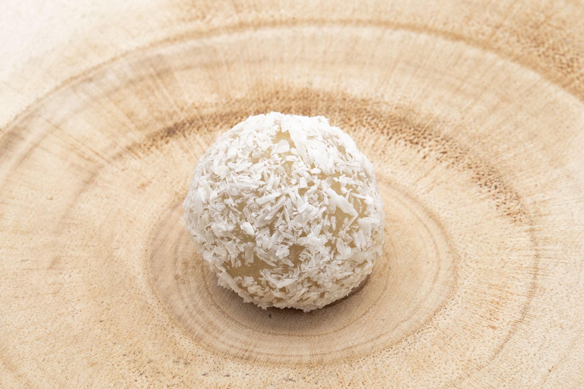 Gros plan d'une boule de noix de coco sur une assiette en bois.