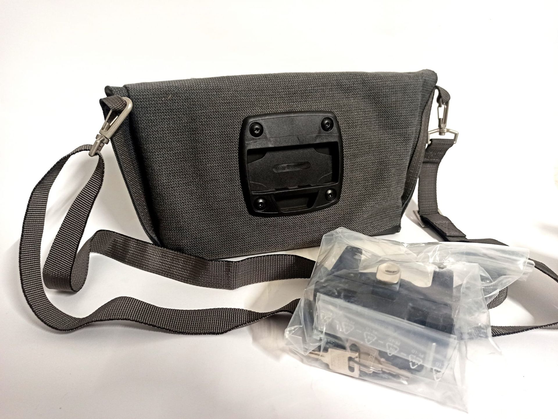 Borsa da bici testurizzata grigia con tracolla e una piccola borsa con accessori di montaggio.