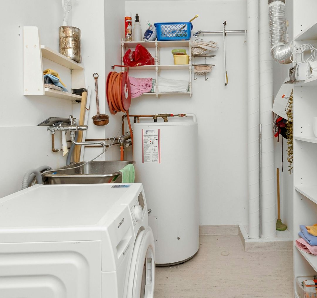 Laundry room with a washing machine, shelves, and water heater.