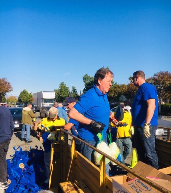 A man in a blue shirt is standing next to a cardboard box that says ' food ' on it
