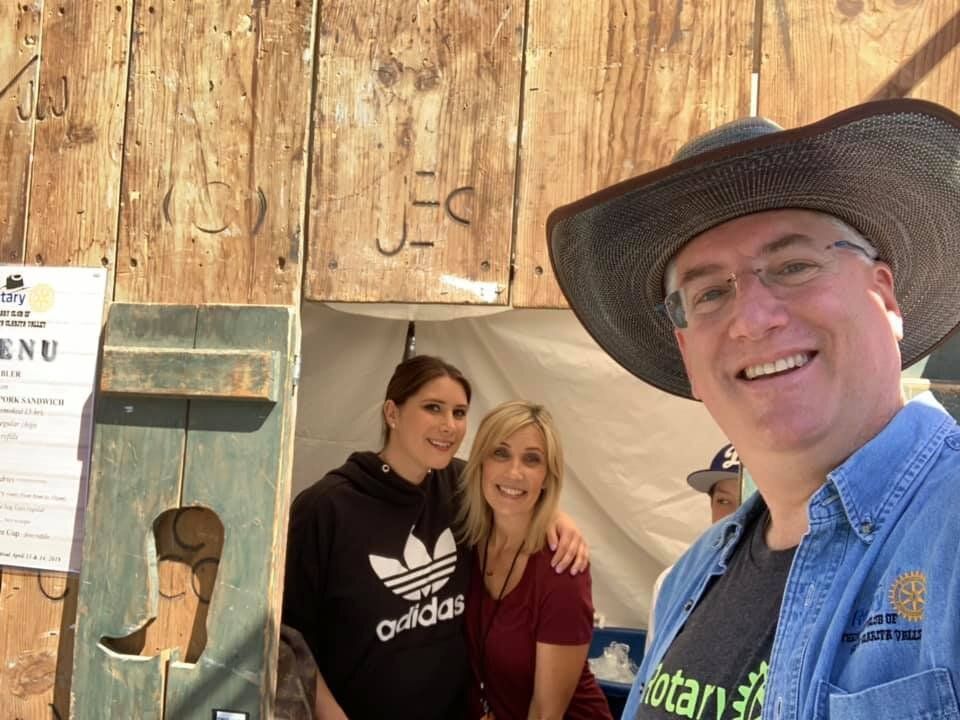 A man wearing a cowboy hat is posing for a picture with two women wearing adidas sweatshirts