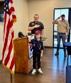 Amos Enderman of Cub Scout Pack 490, president Scott Hoolahan, and Scoutmaster Adam Enderman lead the Pledge of Allegiance to open a Rotary weekly meeting.