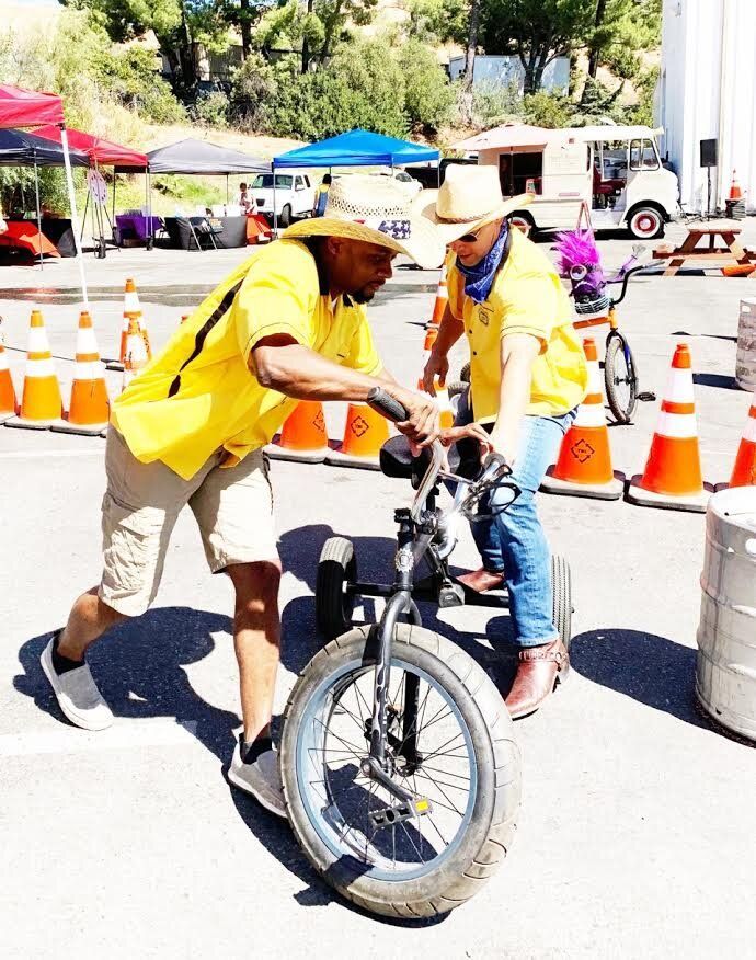 A man in a yellow shirt is helping a child on a bike