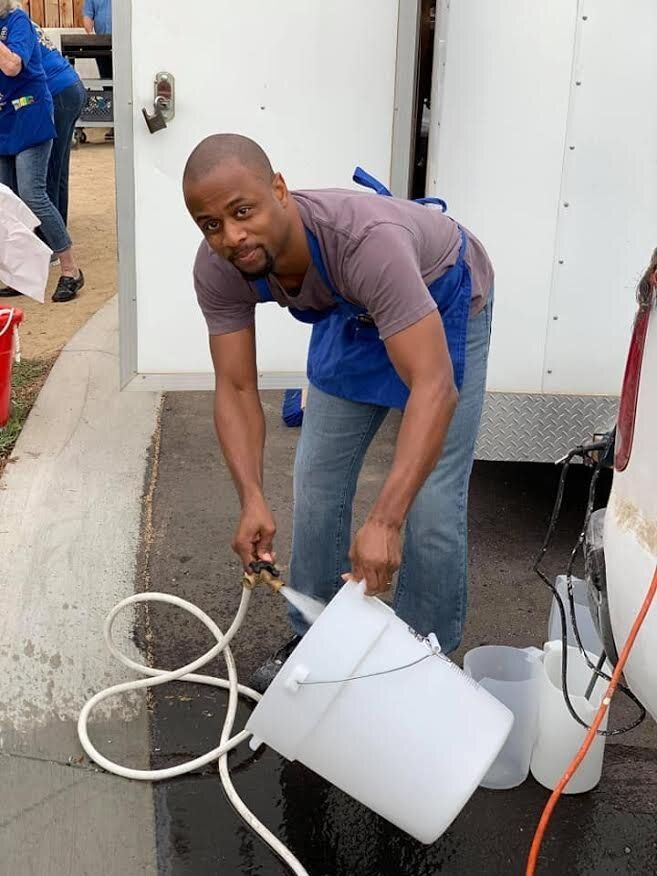 A man is pouring water into a white bucket