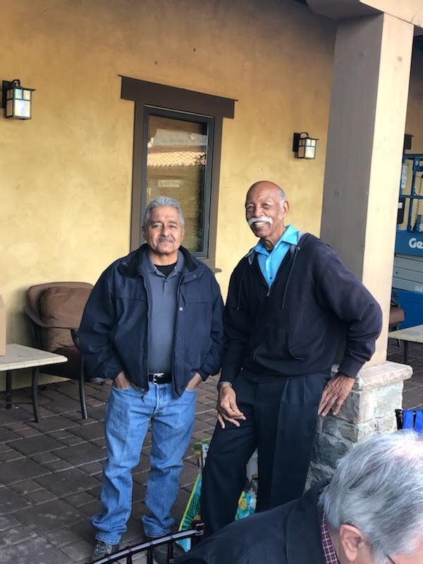 Two men are standing next to each other on a porch.
