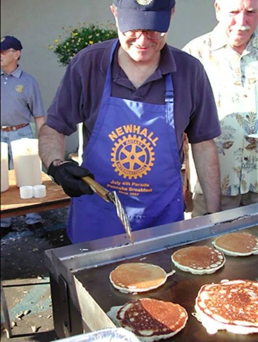 A man wearing a newhall apron is cooking pancakes
