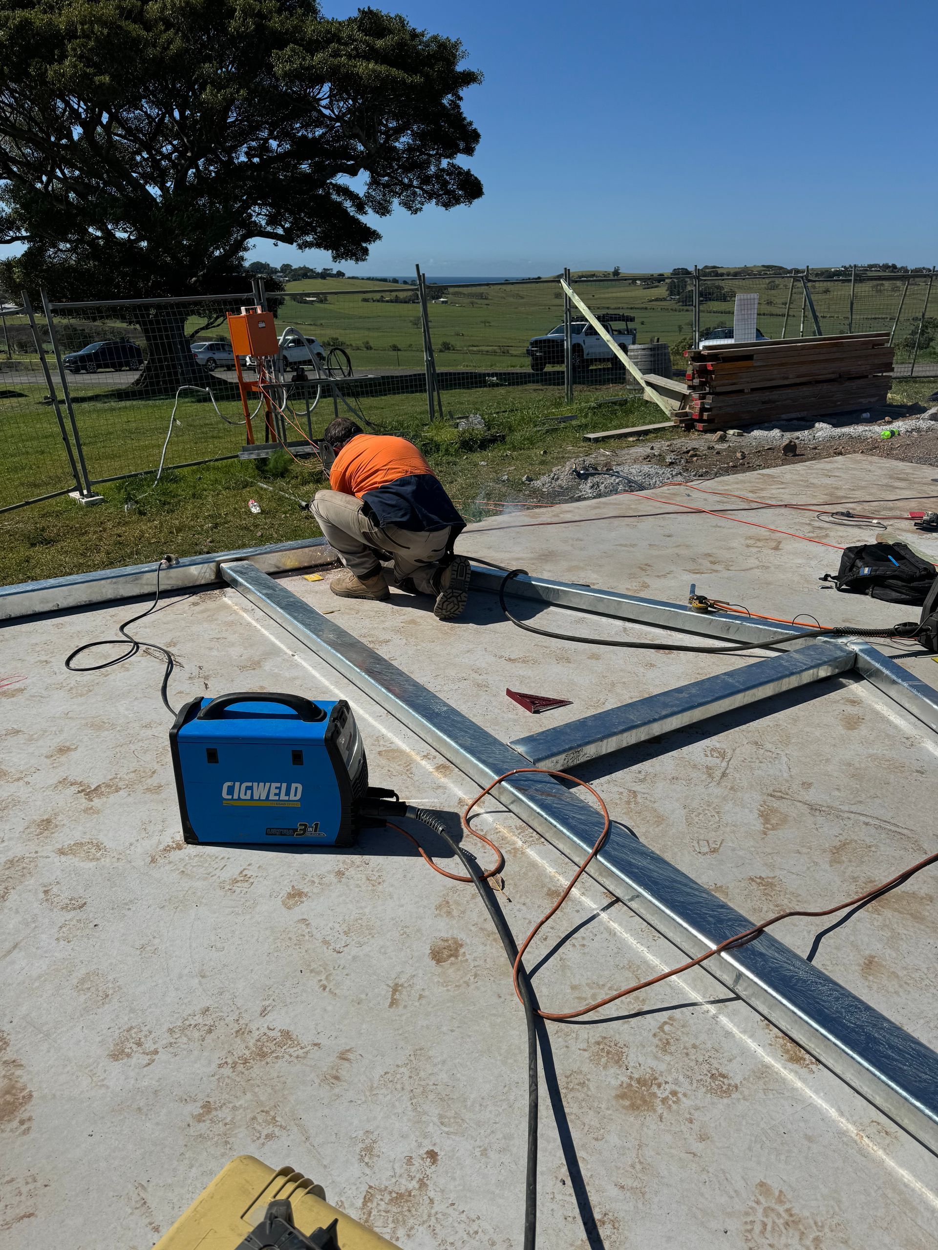 A man is kneeling down on the ground working on a piece of metal.