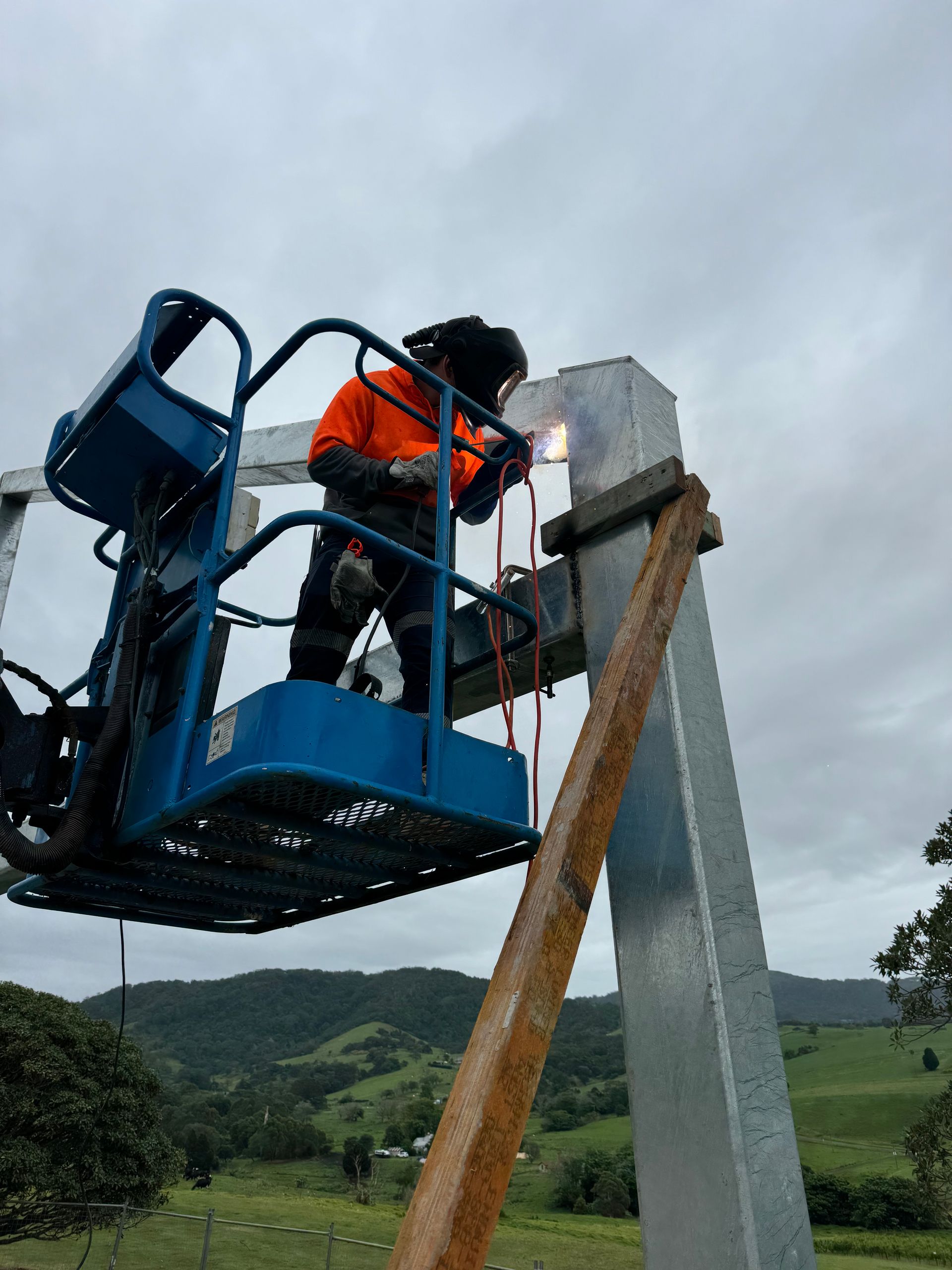 A man is welding a metal pole on a lift.