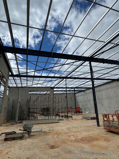The inside of a building under construction with a metal roof.