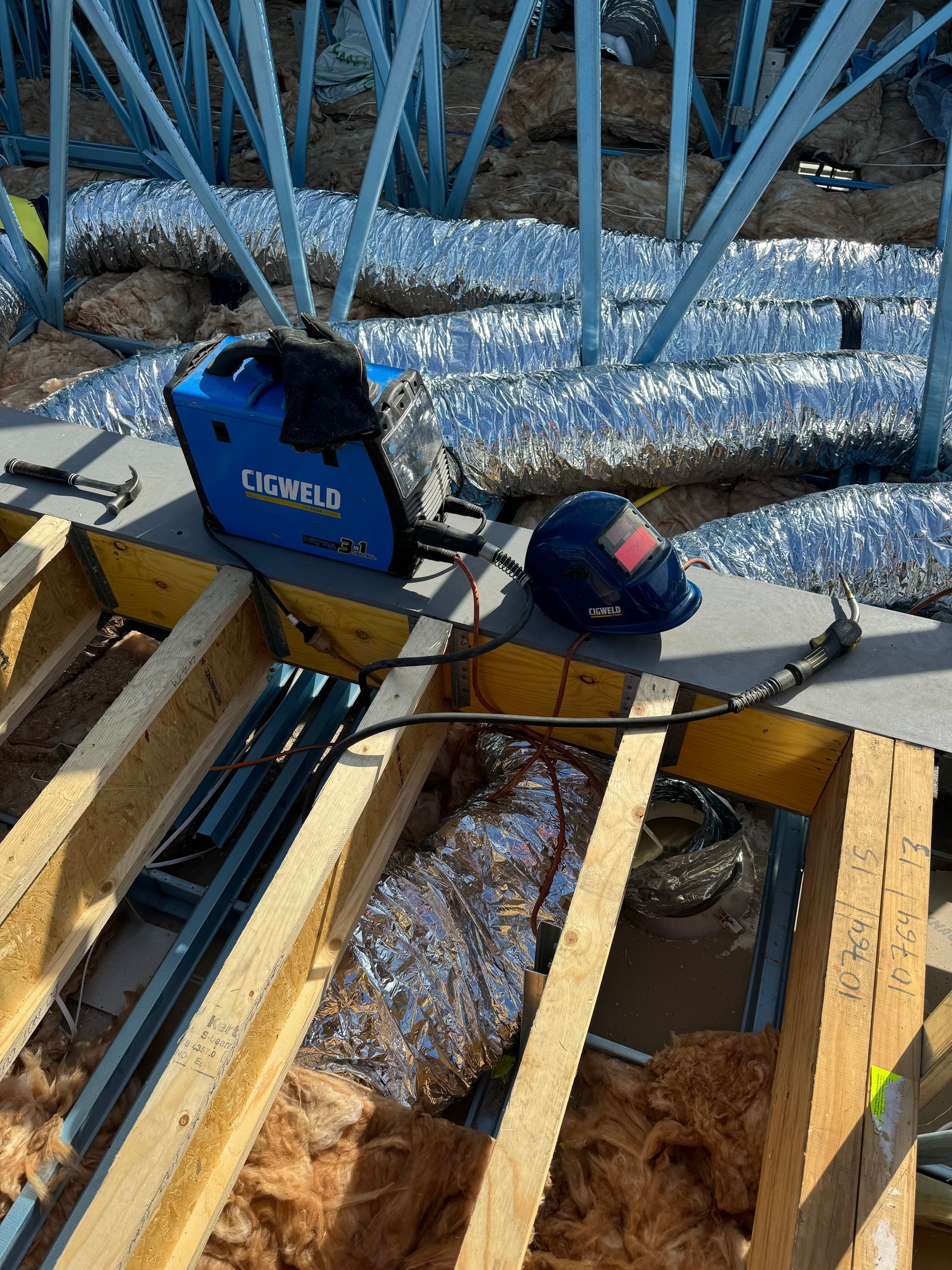A welding machine is sitting on top of a wooden beam.