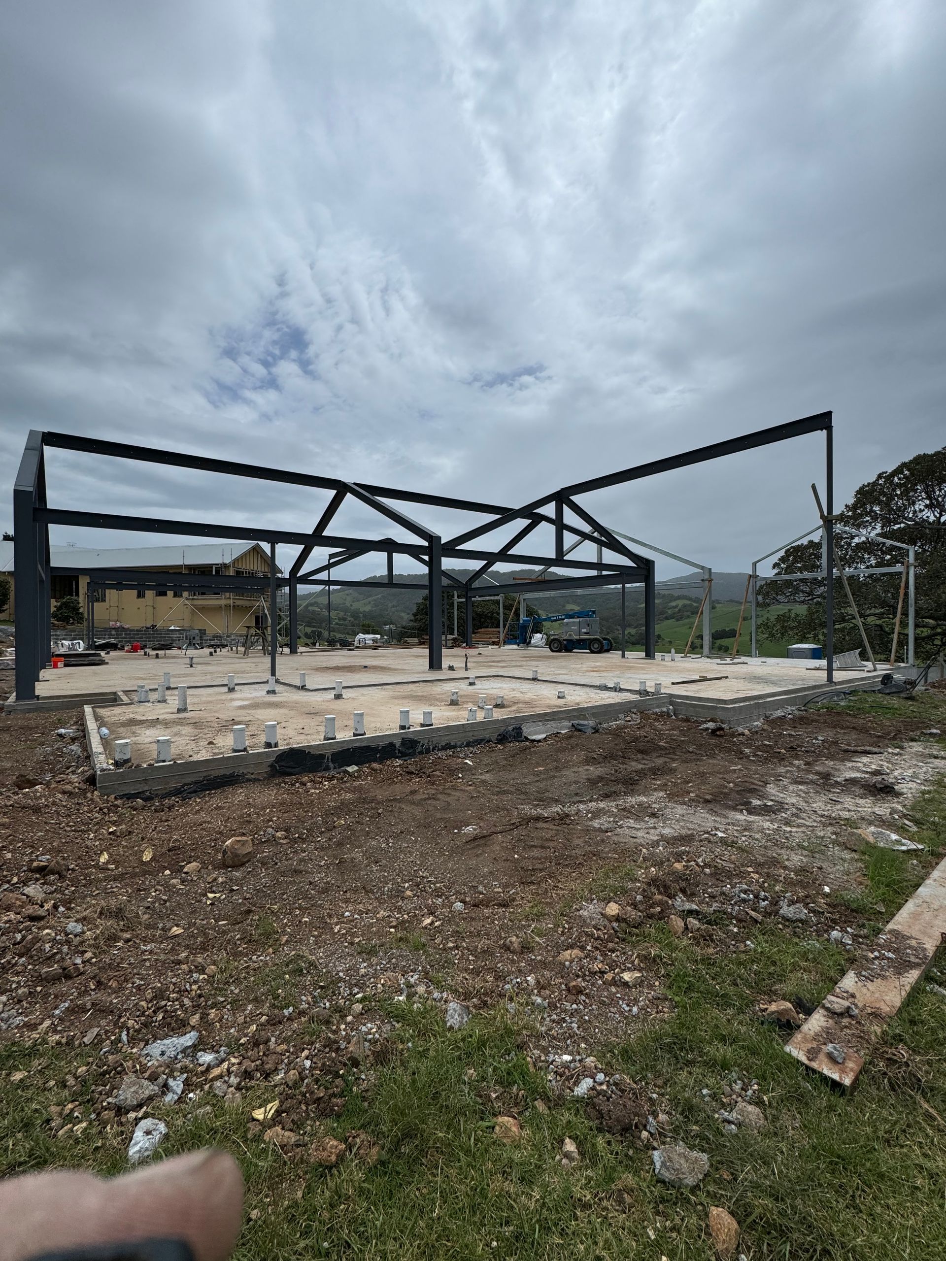 A person is holding a remote control in front of a building under construction.