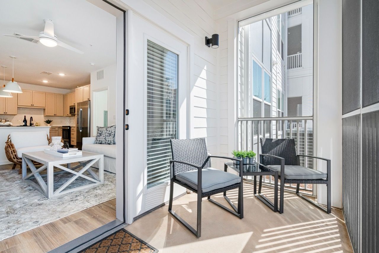 Open-concept living area with kitchen visible and a balcony with seating.