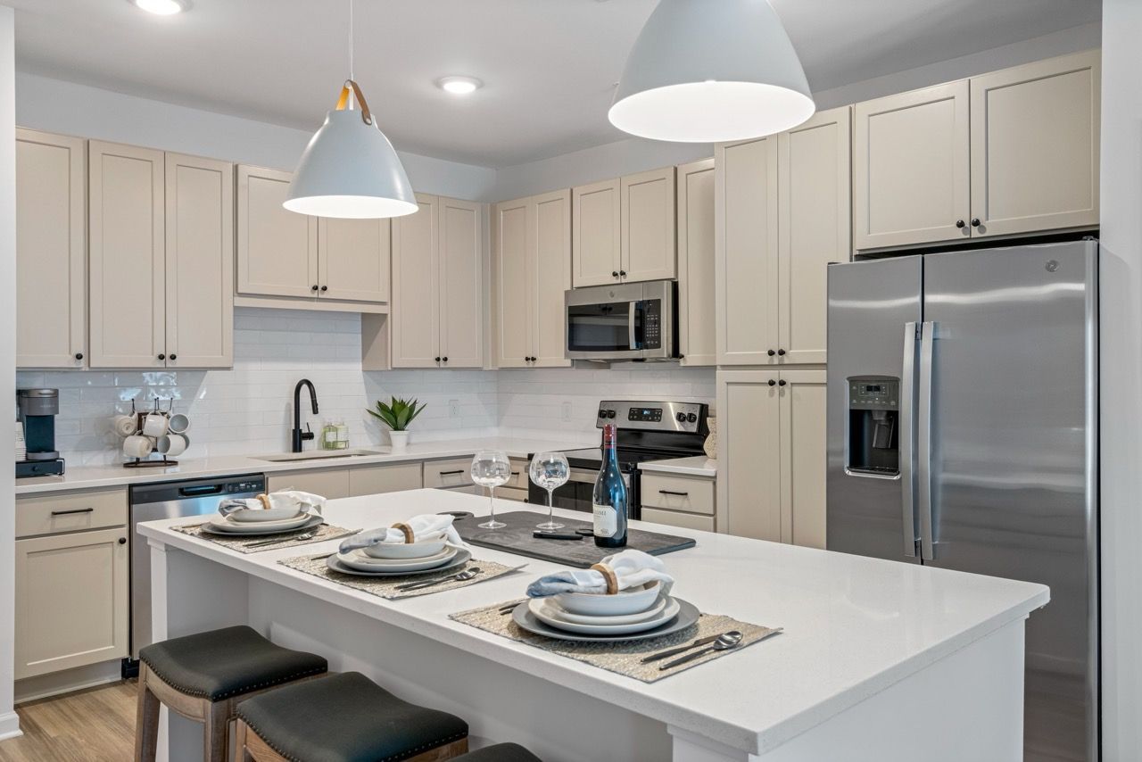 Modern kitchen with white cabinets, stainless steel appliances, and a large island set for dining.