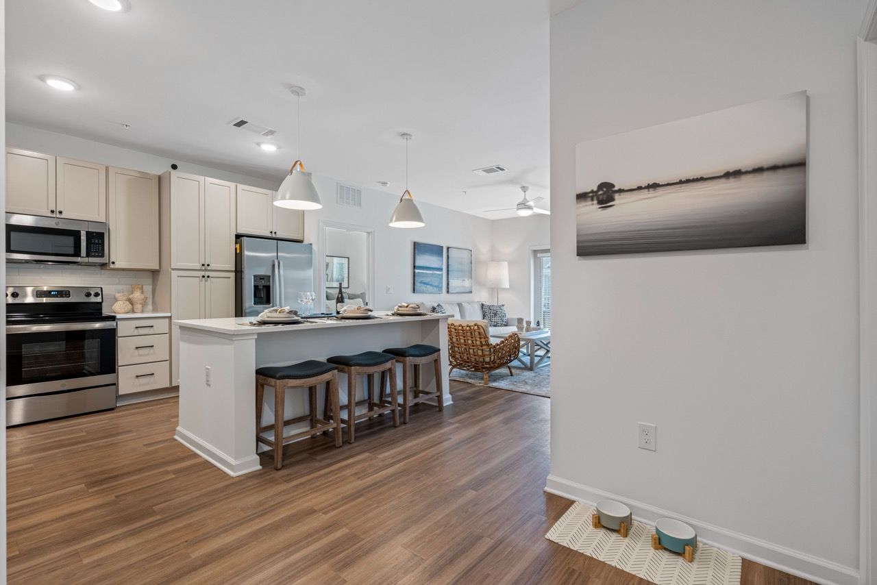 Open-concept kitchen with island, stainless steel appliances, and bar stools.