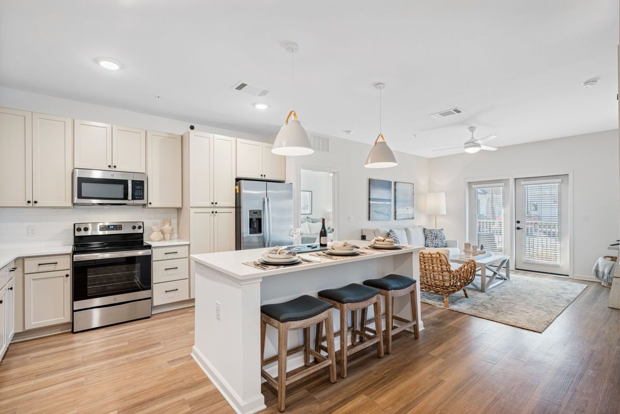 Bright, open-concept kitchen with an island, pendant lights, and a view into the living area.