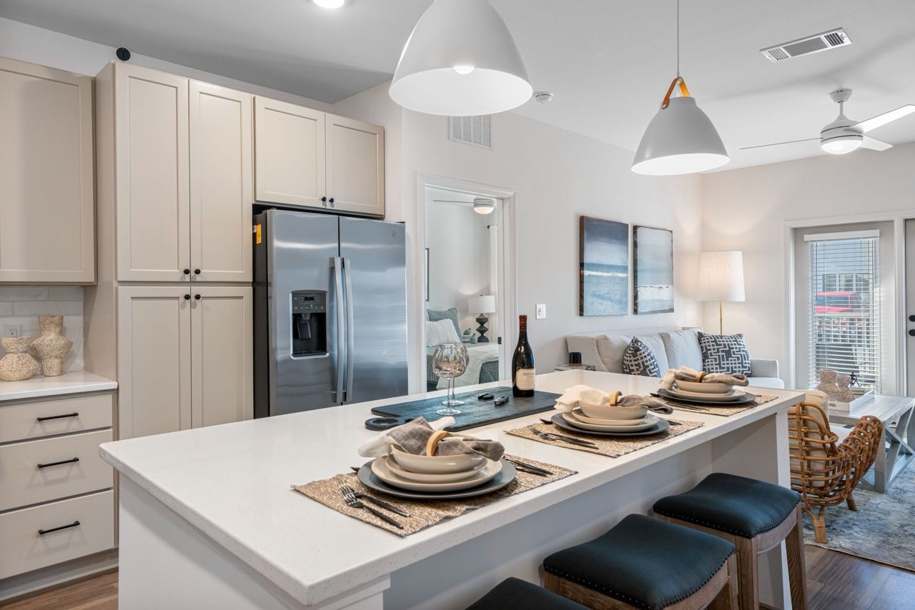 Open-concept kitchen with island, dining area, and living room in a modern apartment.