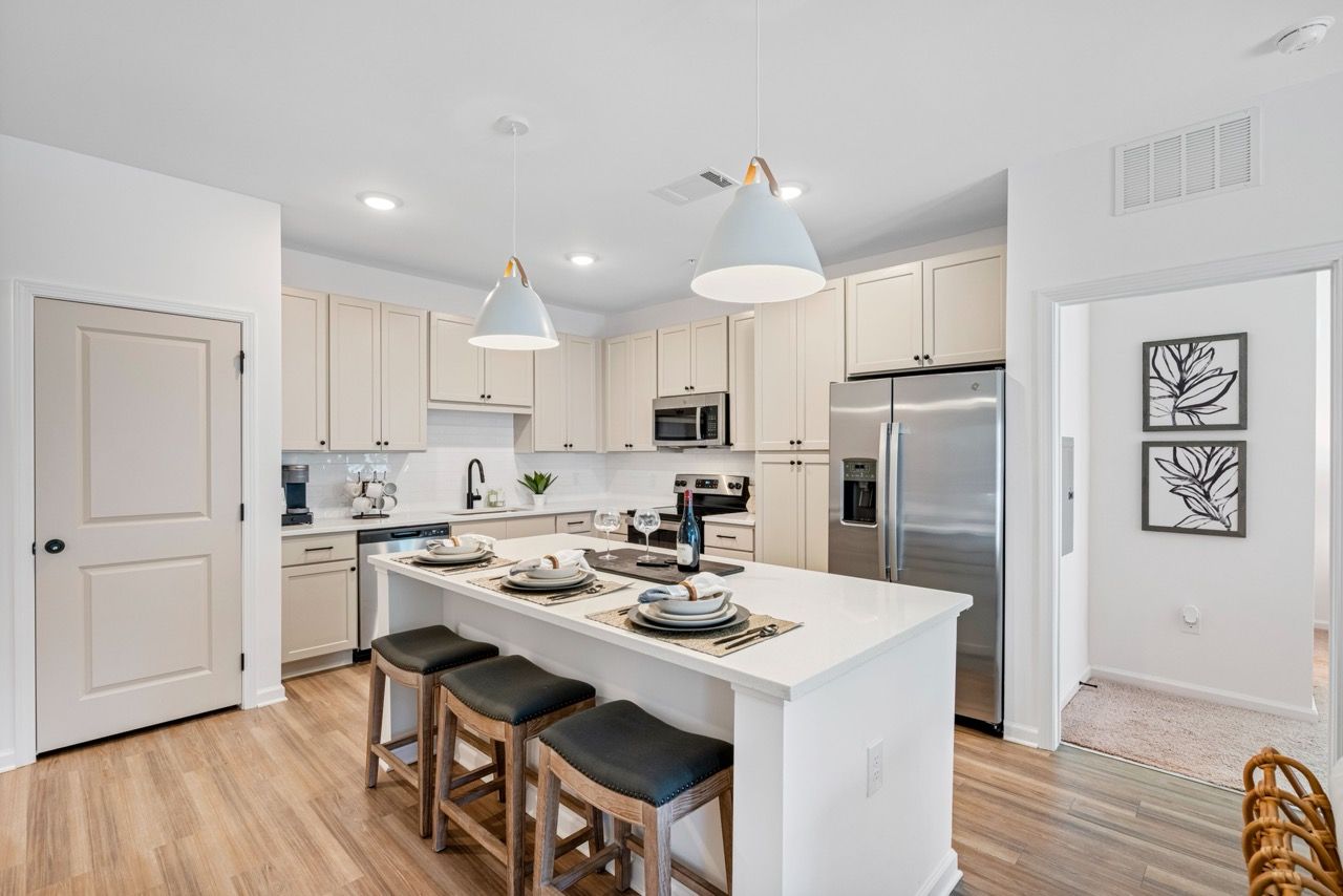 Bright kitchen with white cabinets, stainless steel appliances, and an island with seating.